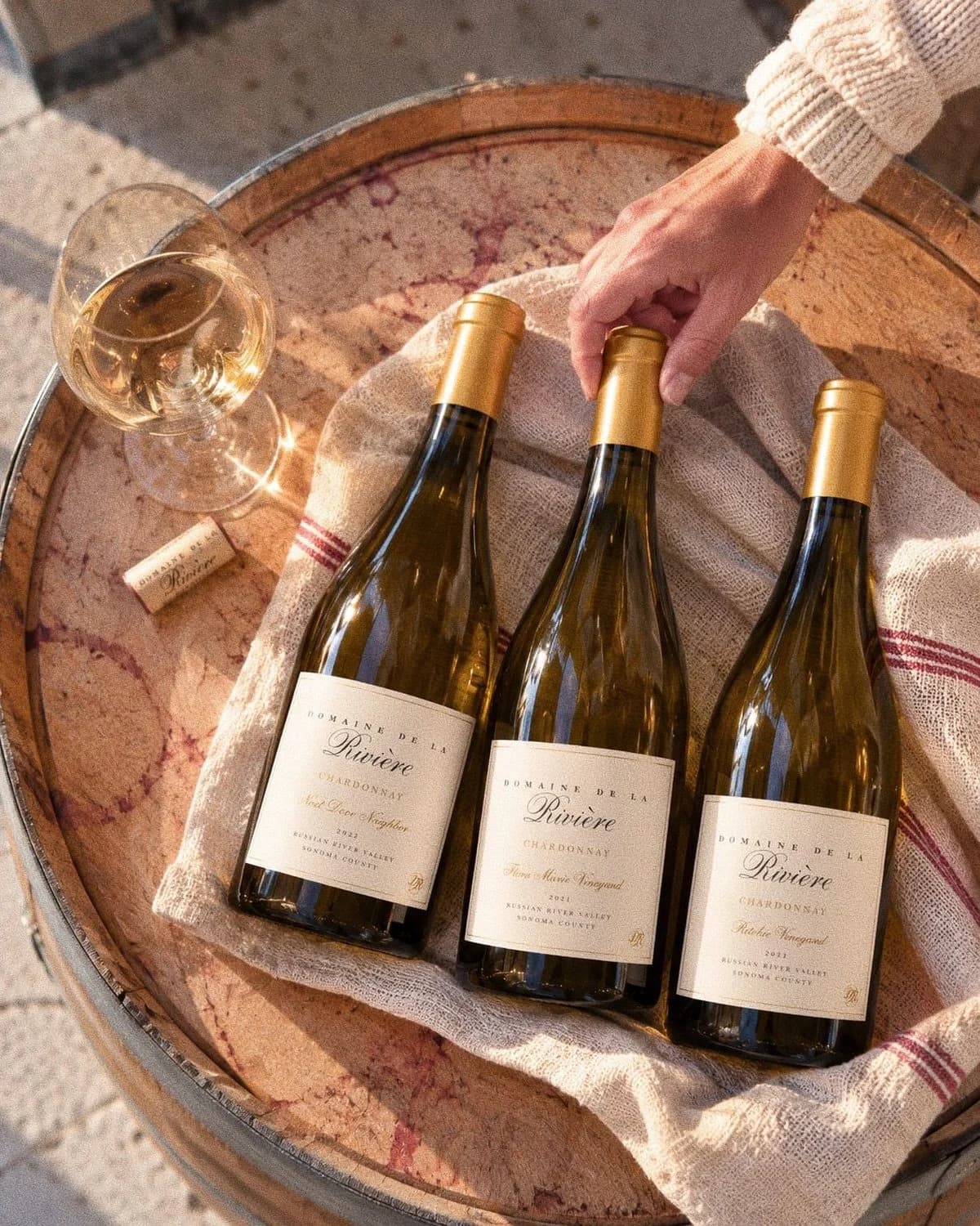 2022 Next Door Neighbor, 2021 Flora Marie, and 2021 Ritchie Vineyard Chardonnay on an oak barrel